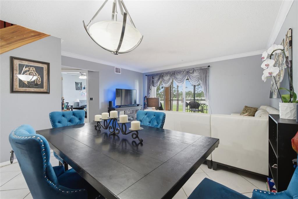 A dining area with a dark table and blue tufted chairs opens to a living room — 2400 FEATHER SOUND DRIVE UNIT 313, CLEARWATER, FL