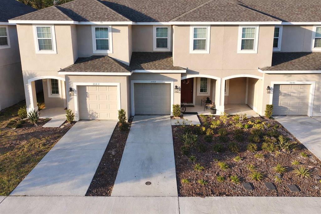 An aerial view shows the front exterior of a multi-unit townhouse with attached garages — 3587 DAVENPORT CREEK COURT, KISSIMMEE, FL