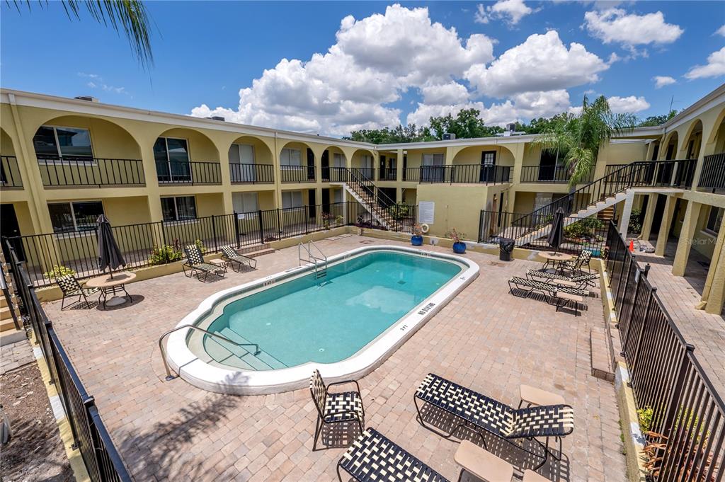 An outdoor swimming pool is surrounded by a paved patio and a two-story apartment building — 3206 W AZEELE STREET UNIT 129, TAMPA, FL
