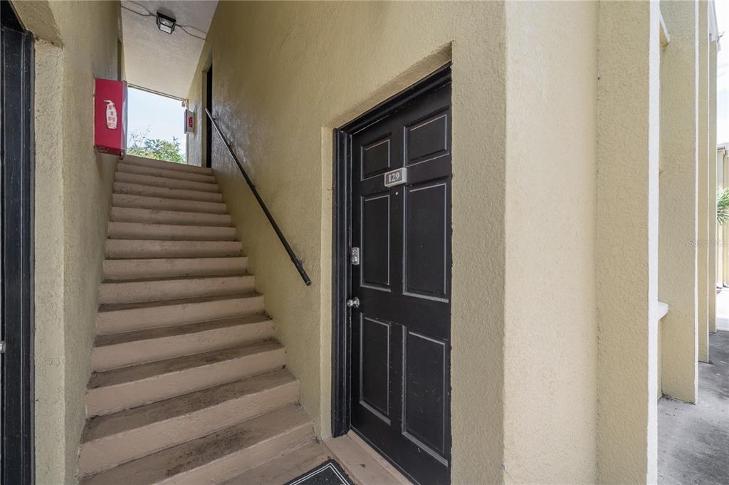 A black front door labeled 129 sits next to a concrete staircase leading upstairs — 3206 W AZEELE STREET UNIT 129, TAMPA, FL