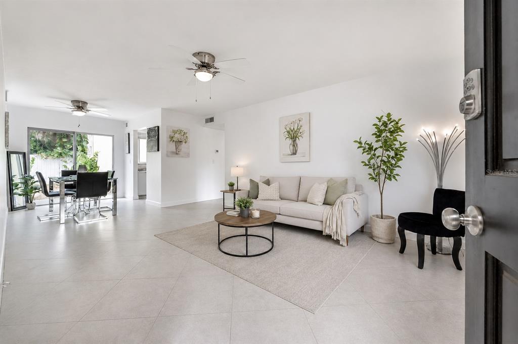 A bright living room features light tile floors, a neutral sofa, and a dining area — 3206 W AZEELE STREET UNIT 129, TAMPA, FL