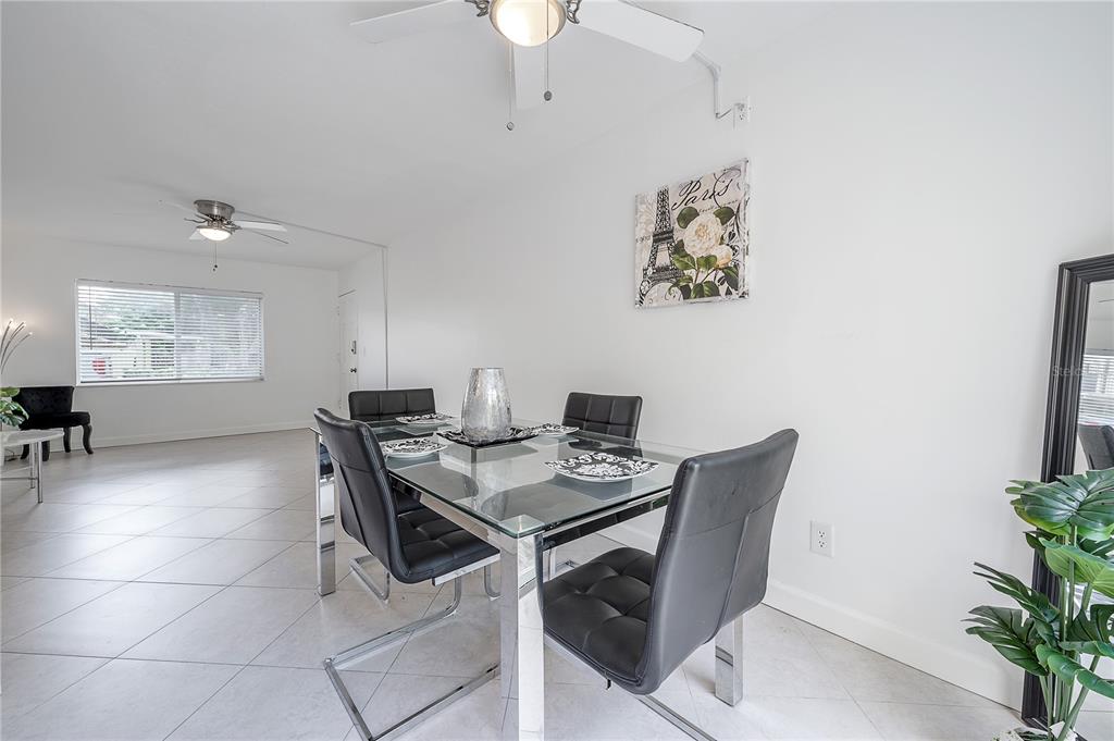 A dining area features a glass table with four black chairs and white tile floors — 3206 W AZEELE STREET UNIT 129, TAMPA, FL