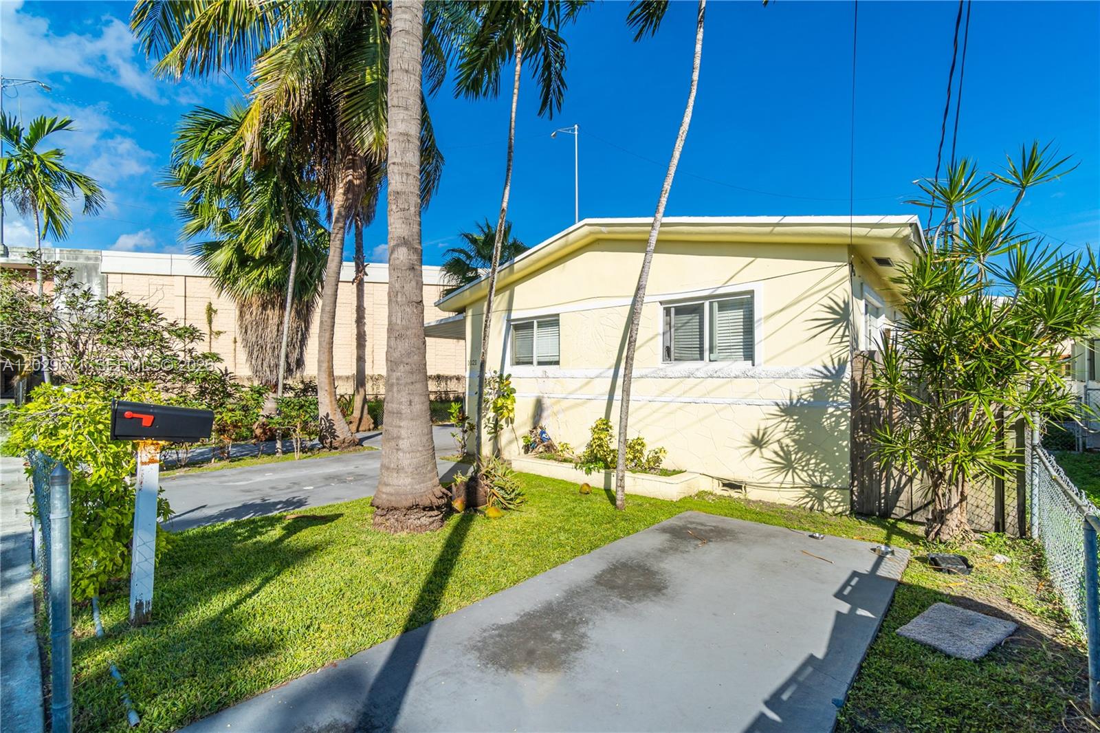 A yellow single-story house with a palm tree, a driveway, and a mailbox in front — 1021 NW 23rd Ave # 1023, Miami FL 33125, MIAMI, FL