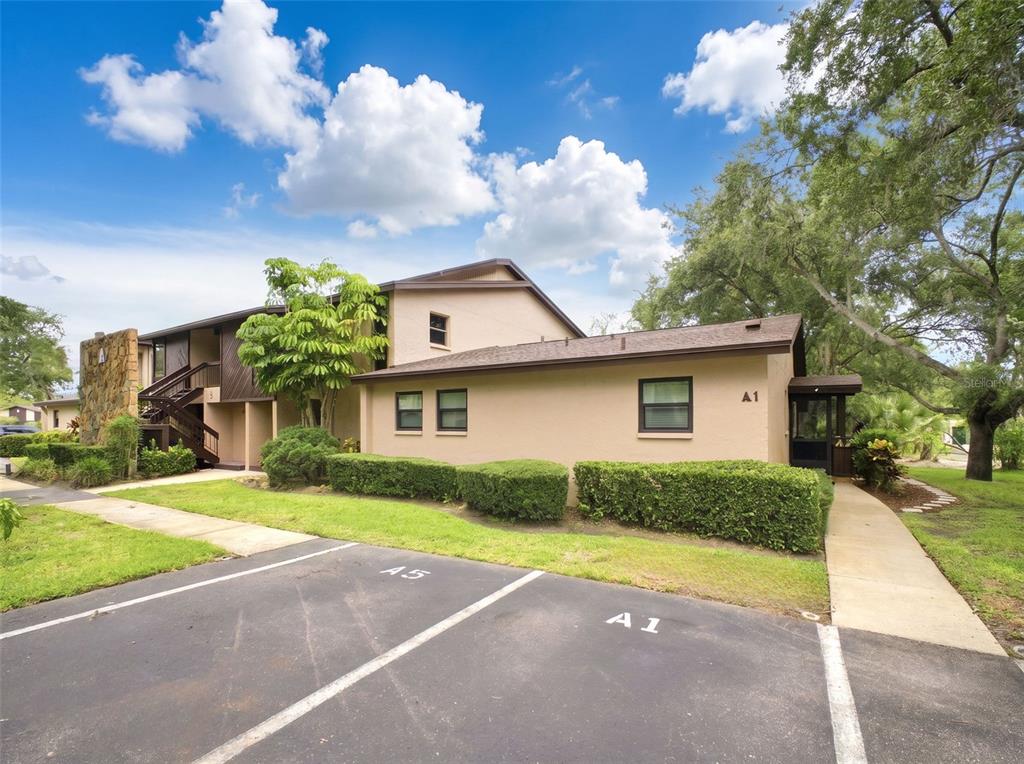 A tan, two-story apartment building with a parking space labeled A1 in the foreground — 1400 TARPON WOODS BOULEVARD UNIT A1, PALM HARBOR, FL
