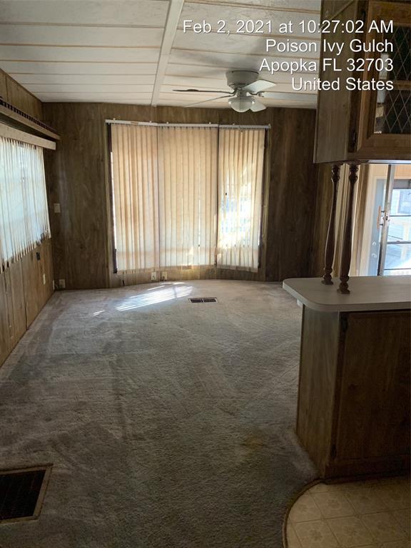 A living room features wood-paneled walls, carpeted flooring, vertical blinds, and a ceiling fan — 3000 CLARCONA ROAD UNIT 616, APOPKA, FL
