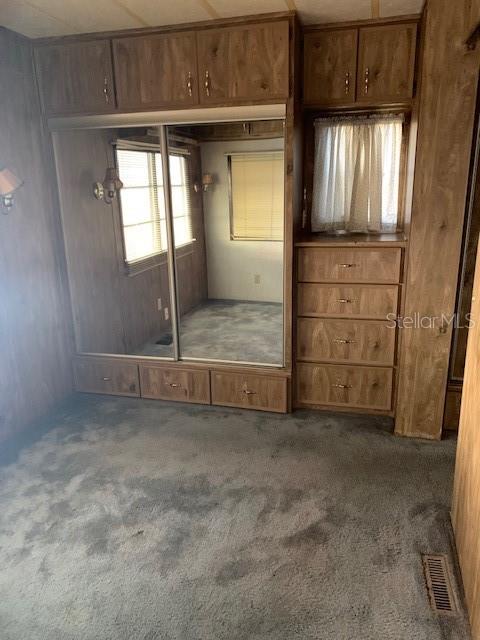 A bedroom features wood-paneled walls, a mirrored sliding closet, built-in drawers, and gray carpeting — 3000 CLARCONA ROAD UNIT 616, APOPKA, FL