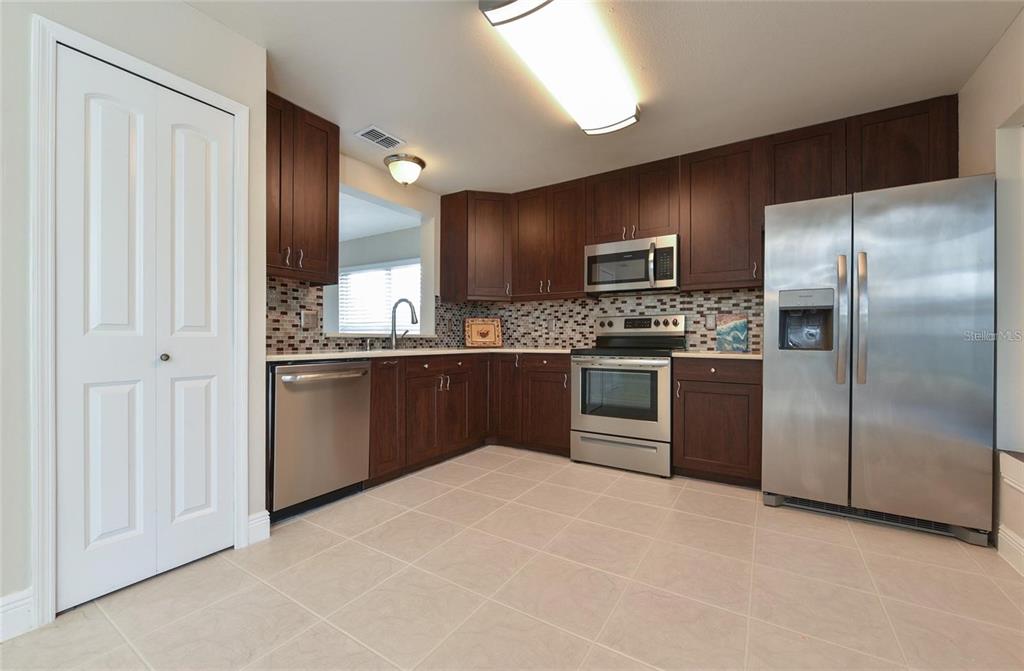 A kitchen features dark wood cabinets, stainless steel appliances, and a tiled backsplash — 9551 CHANDON DRIVE, ORLANDO, FL
