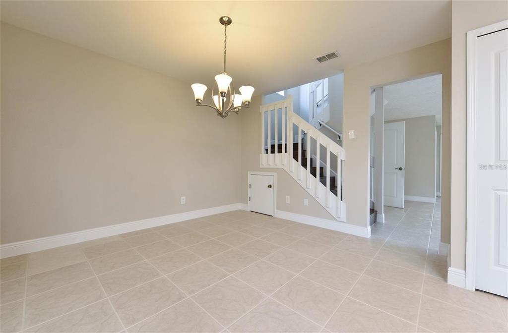 A dining area features tile flooring, a chandelier, and a staircase with white railings — 9551 CHANDON DRIVE, ORLANDO, FL