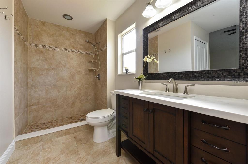 A bathroom features a walk-in tiled shower, a white toilet, and a dark wood vanity — 9551 CHANDON DRIVE, ORLANDO, FL