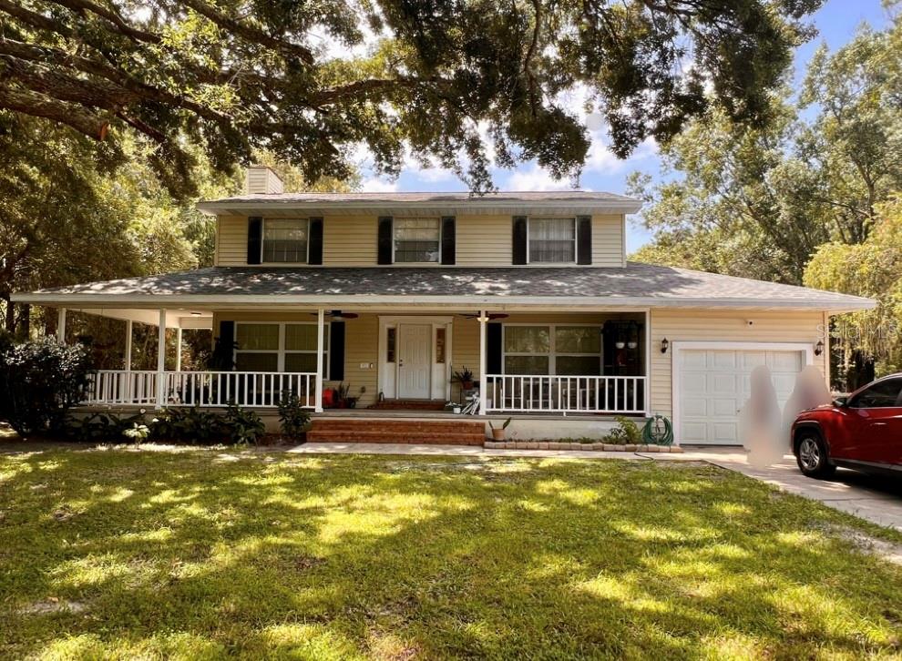 A two-story house with beige siding, a large front porch, and an attached garage — 4784 OREN BROWN ROAD, KISSIMMEE, FL