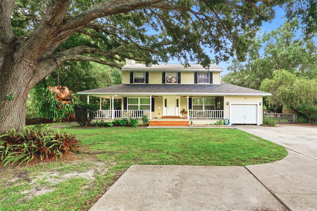 A two-story house with a wrap-around porch, a single-car garage, and a large oak tree — 4784 OREN BROWN ROAD, KISSIMMEE, FL