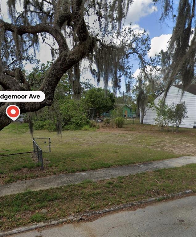 A vacant grassy lot sits between a white house and a large oak tree — 1131 EDGEMOOR AVENUE, SEBRING, FL