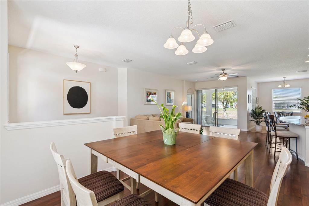 A dining area with a wooden table and chairs sits adjacent to a living room — 26645 MANASSAS DRIVE, LEESBURG, FL