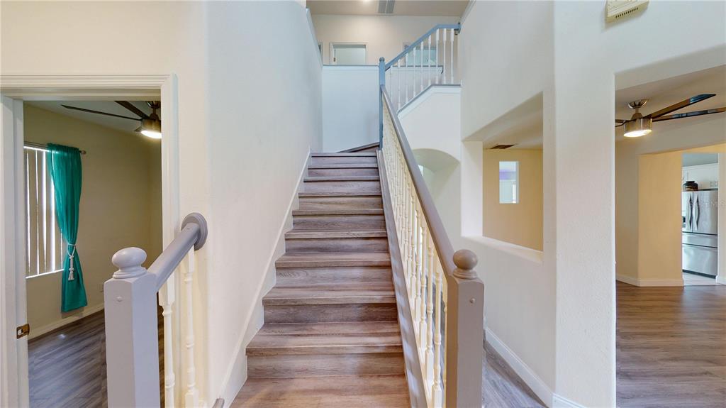 A staircase with wood-look steps and a white railing leads to an upper landing — 3044 CAMINO REAL DRIVE S, KISSIMMEE, FL