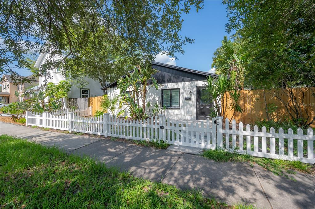 A white house with a black roof and trim sits behind a white picket fence — 6901 S FITZGERALD STREET, TAMPA, FL