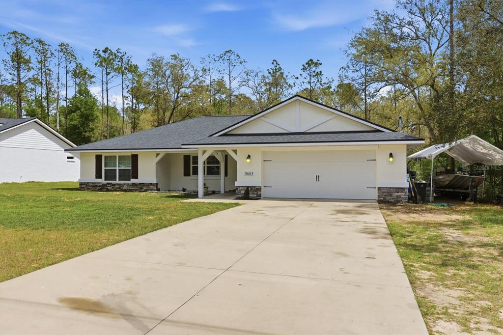 A single-story house with a white exterior, stone accents, and a two-car garage — 8683 N TEATHER TERRACE, DUNNELLON, FL