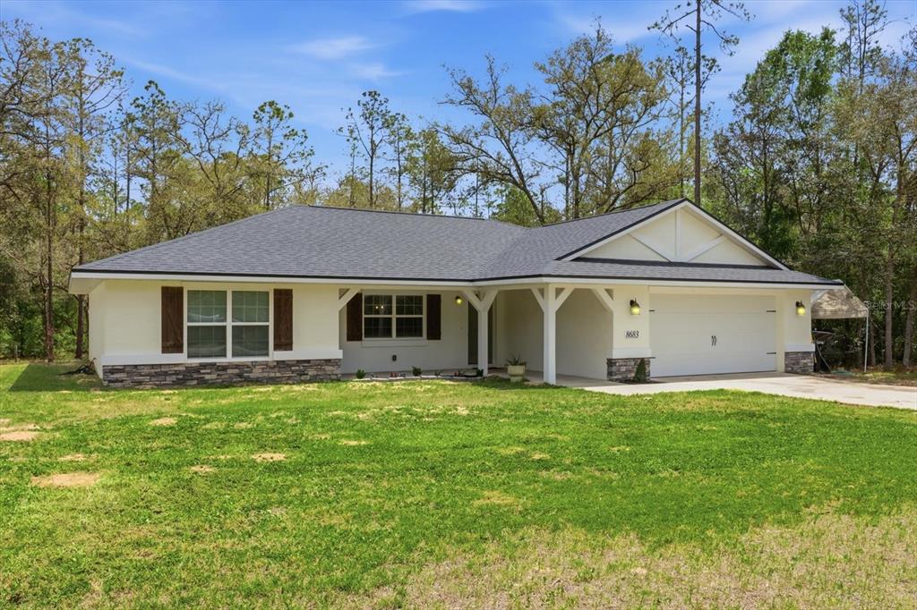 A single-story house with a white exterior, stone accents, and a two-car garage — 8683 N TEATHER TERRACE, DUNNELLON, FL