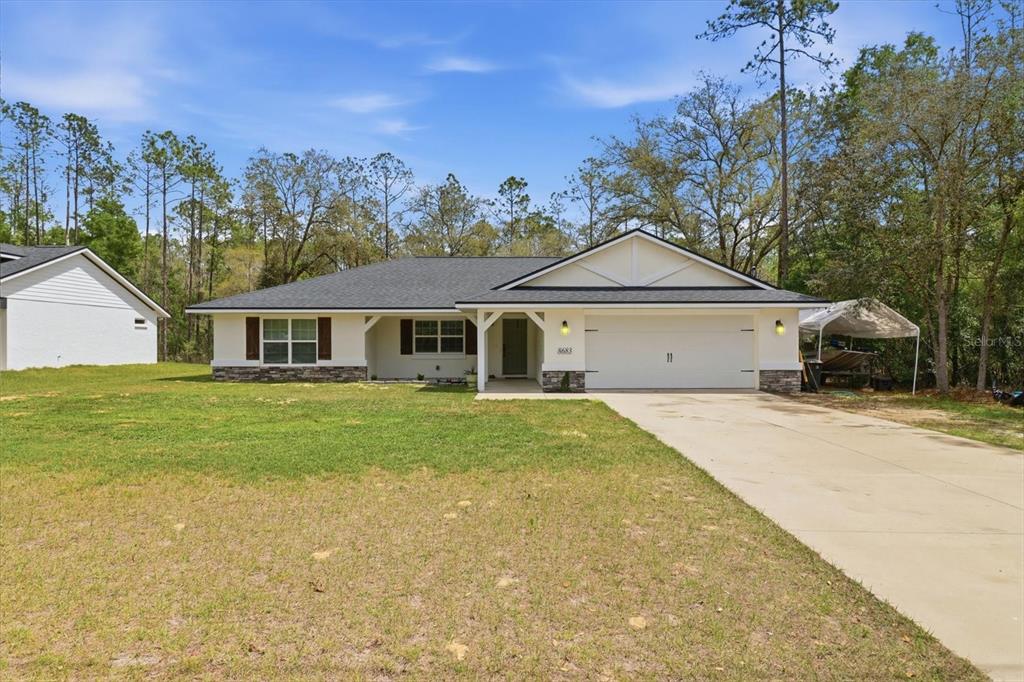 A single-story house with a white exterior, stone accents, and a two-car garage — 8683 N TEATHER TERRACE, DUNNELLON, FL