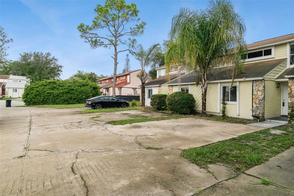 A concrete driveway leads to the front entrance of a two-story townhouse with palm trees — 2835 HUNT CLUB LANE, ORLANDO, FL