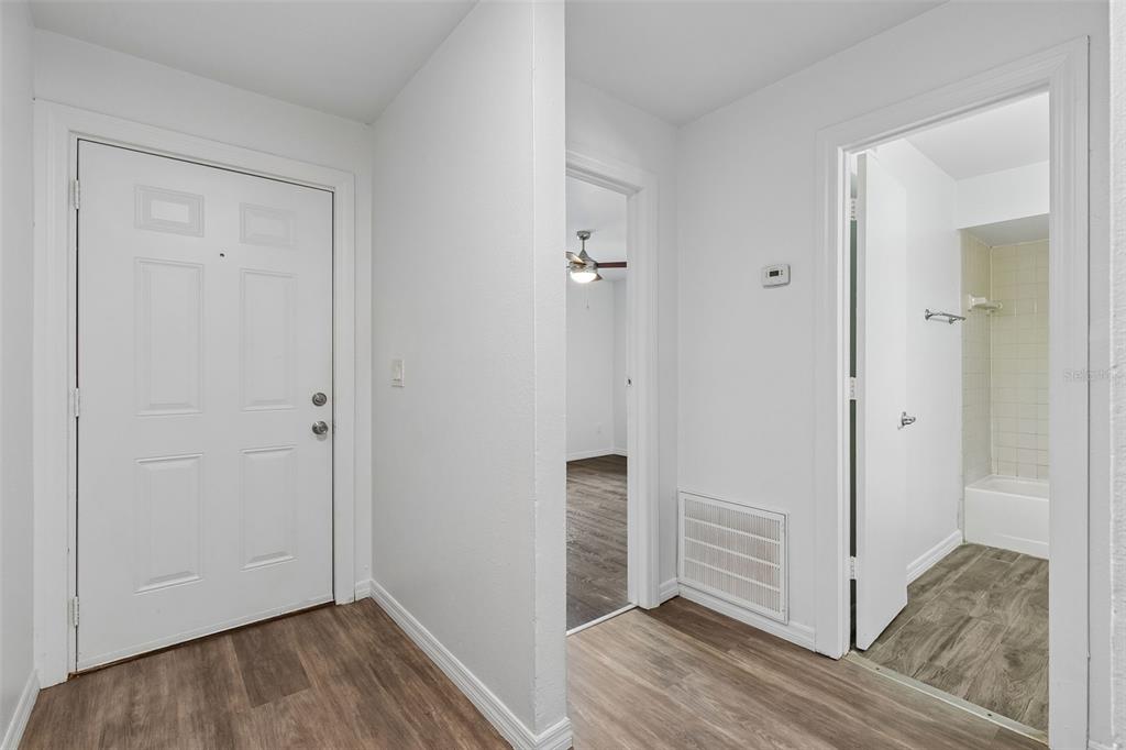 An interior view showing a white front door, a hallway, and a bathroom entrance — 2835 HUNT CLUB LANE, ORLANDO, FL