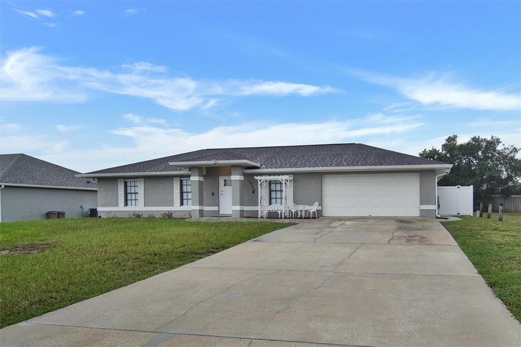 A single-story gray house with a white front door, a two-car garage, and a driveway — 2728 COURTLAND BOULEVARD, DELTONA, FL