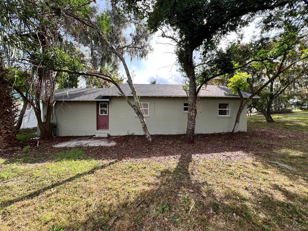 The exterior of a single-story house with tan painted brick walls and a dark door — 107 OAKLAND DRIVE, DELAND, FL