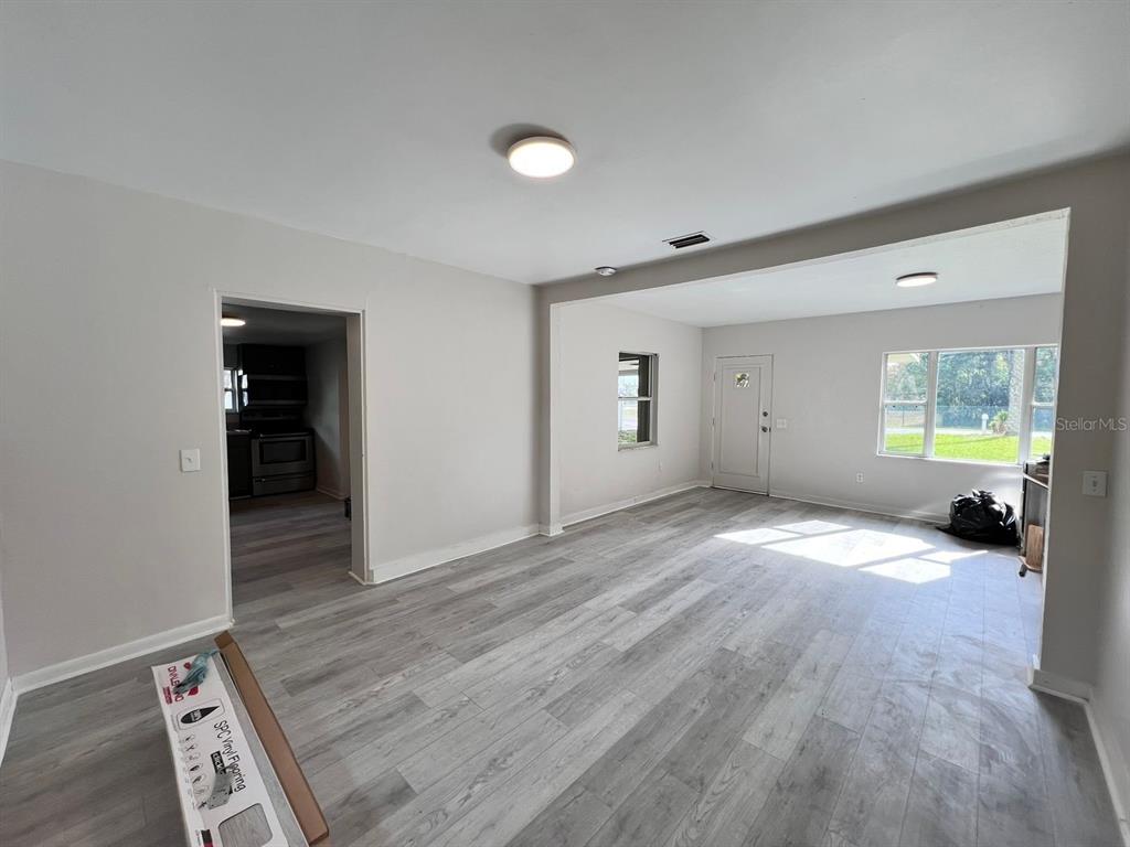 An interior view of a living room with light gray wood-look flooring and white walls — 107 OAKLAND DRIVE, DELAND, FL
