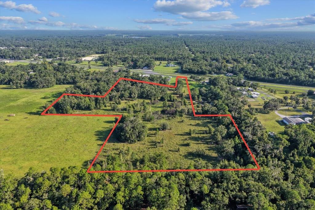 An aerial view shows a large, irregularly shaped plot of land outlined in red — NE HWY 27TH, BRONSON, FL