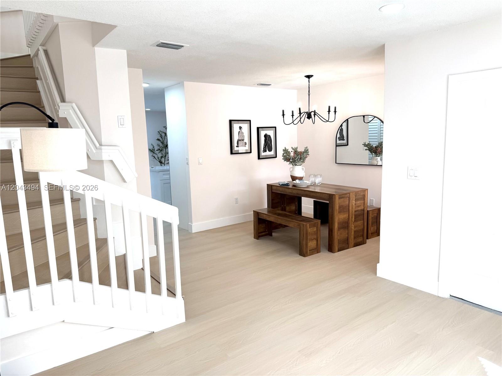 A dining area with a wooden table and bench sits beside a staircase with white railings — 6350 SW 139th Ave, Miami FL 33183, MIAMI, FL