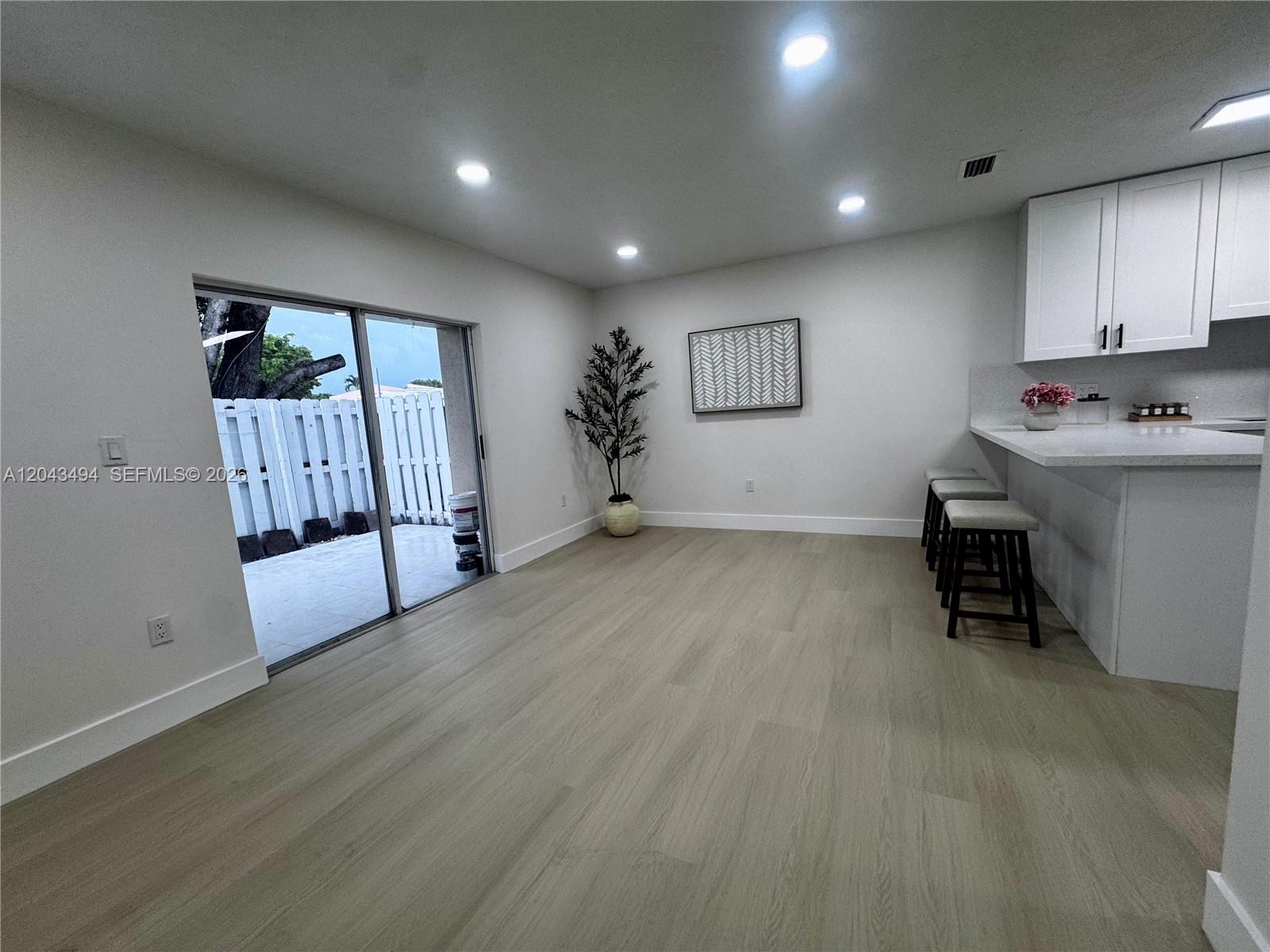 A bright dining area features light wood flooring, a sliding glass door, and kitchen bar seating — 6350 SW 139th Ave, Miami FL 33183, MIAMI, FL