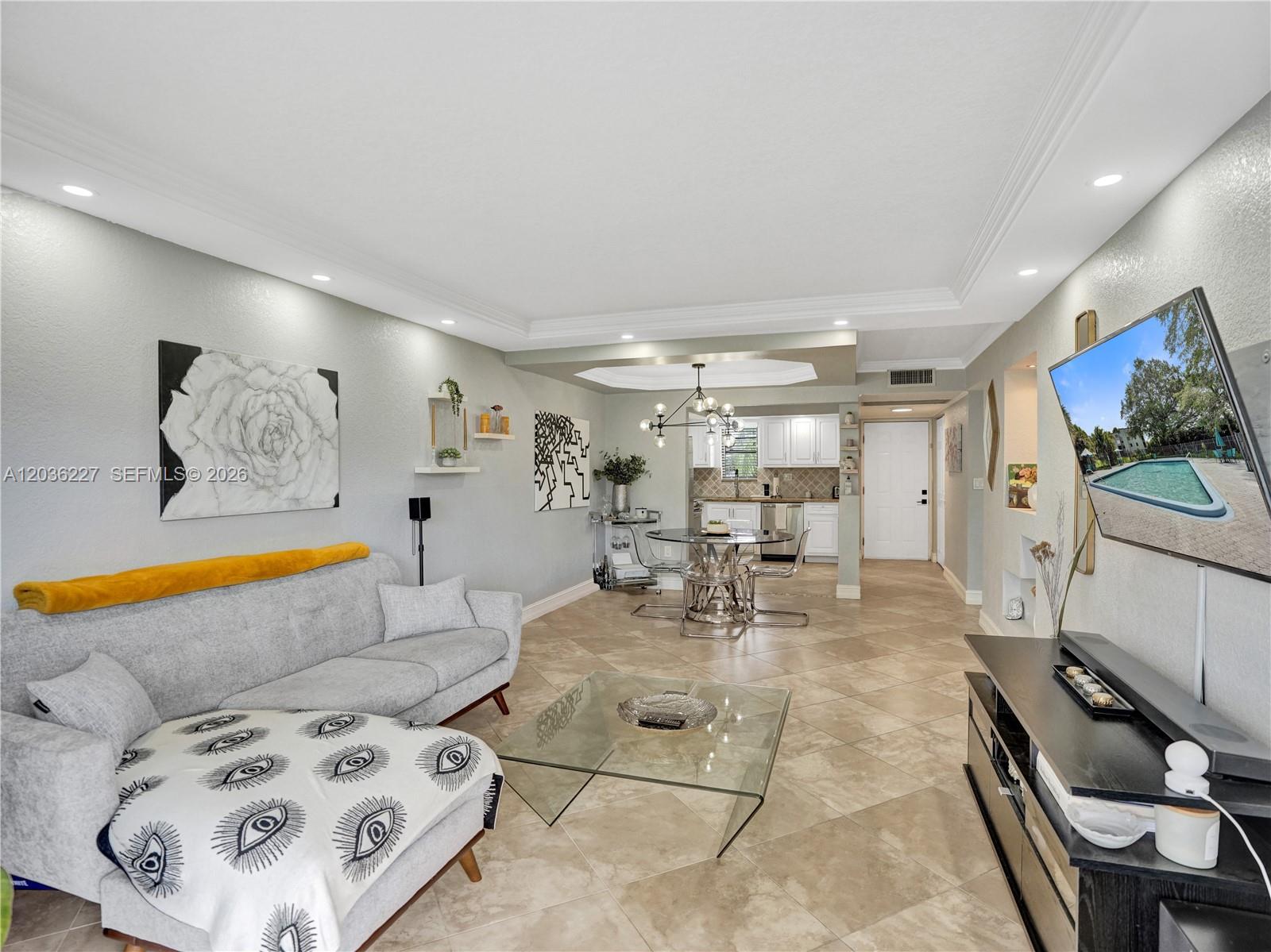 A living room with a grey sofa, glass coffee table, and an open-concept dining area — 9440 SW 8th St # 309, Boca Raton FL 33428, BOCA RATON, FL