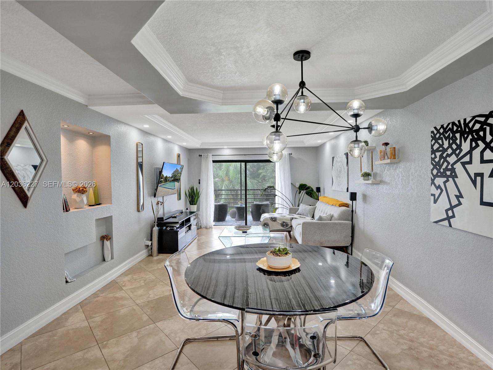 A dining area with a round table and clear chairs opens into a living room — 9440 SW 8th St # 309, Boca Raton FL 33428, BOCA RATON, FL