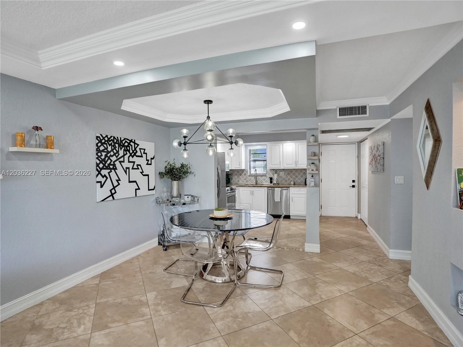 A dining area with a glass table and modern chandelier sits adjacent to a kitchen — 9440 SW 8th St # 309, Boca Raton FL 33428, BOCA RATON, FL