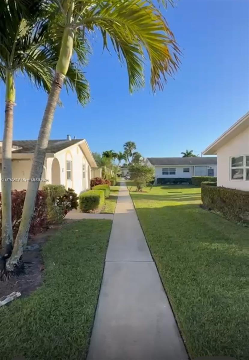 A concrete walkway leads between two single-story residential buildings surrounded by lawns and palm trees — 2622 E Emory Drive # I, West Palm Beach FL 33415, WEST PALM BEACH, FL