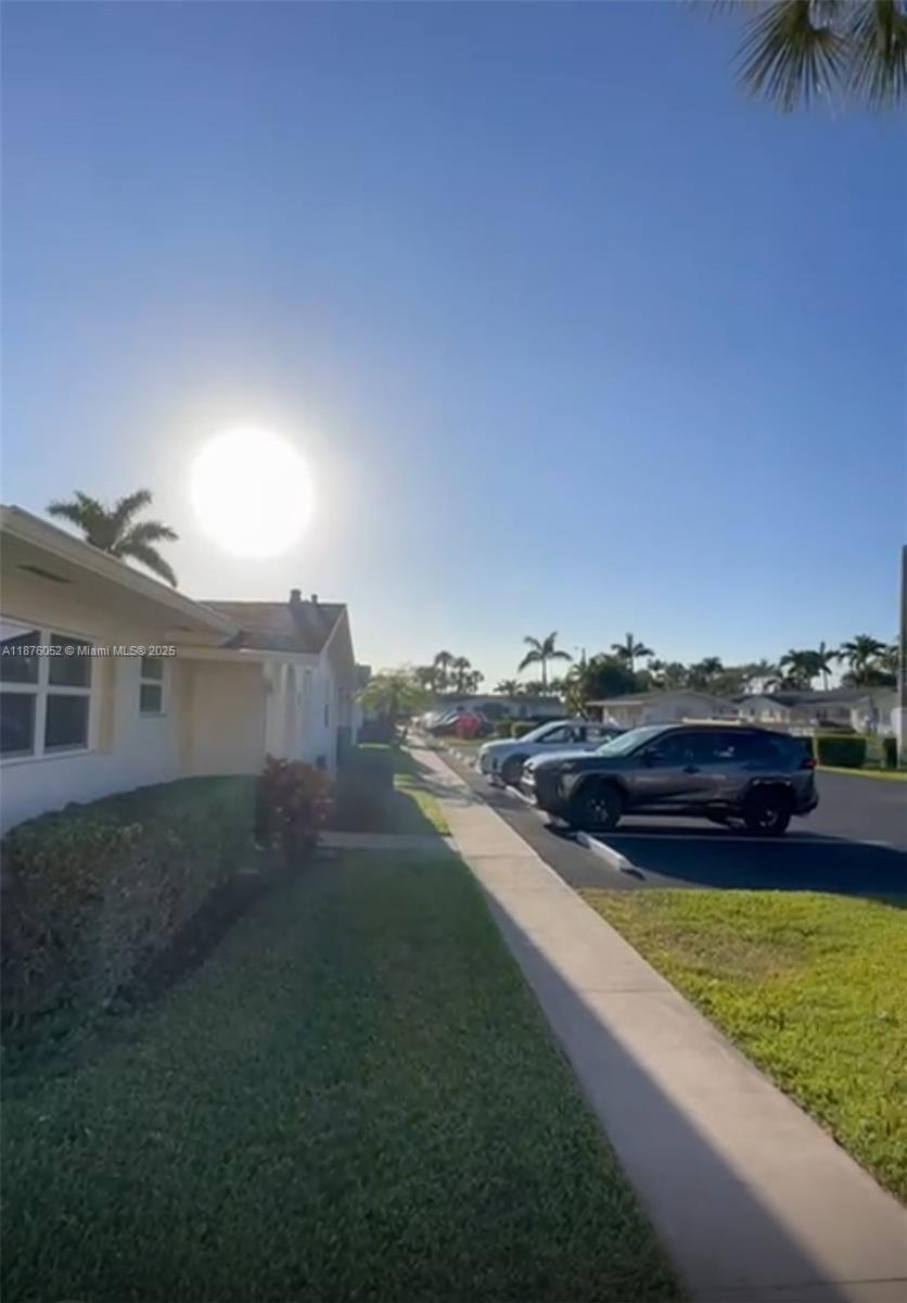 A view of a residential street with parked cars and a house exterior under sunlight — 2622 E Emory Drive # I, West Palm Beach FL 33415, WEST PALM BEACH, FL