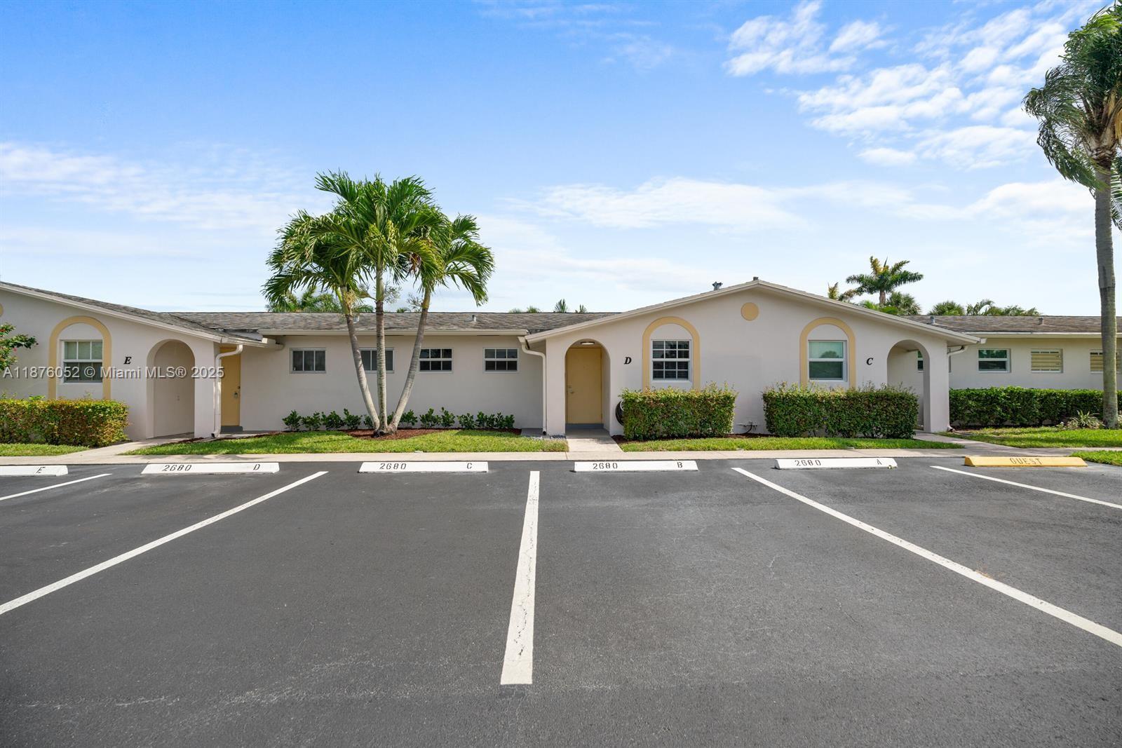 A single-story apartment building exterior features labeled unit entrances and assigned parking spaces — 2622 E Emory Drive # I, West Palm Beach FL 33415, WEST PALM BEACH, FL
