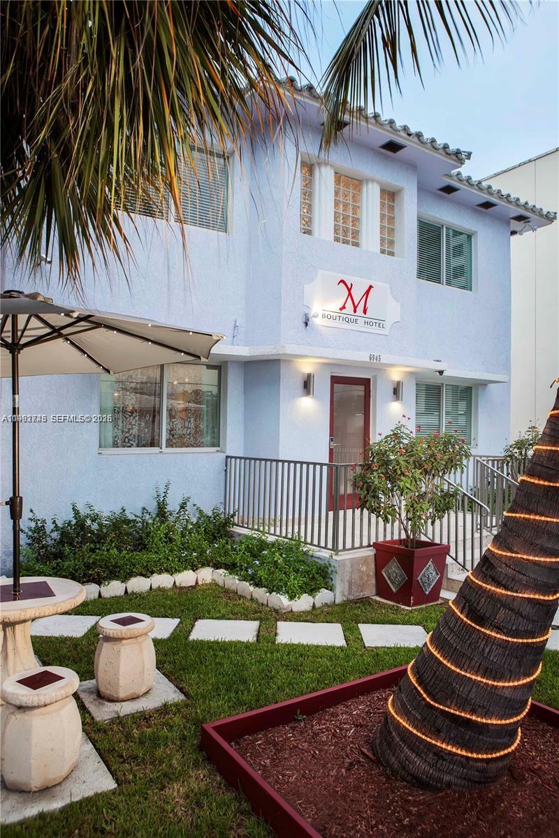 The exterior of a light blue two-story boutique hotel features a palm tree and landscaping — 6945 Abbott Ave, Miami Beach FL 33141, MIAMI BEACH, FL