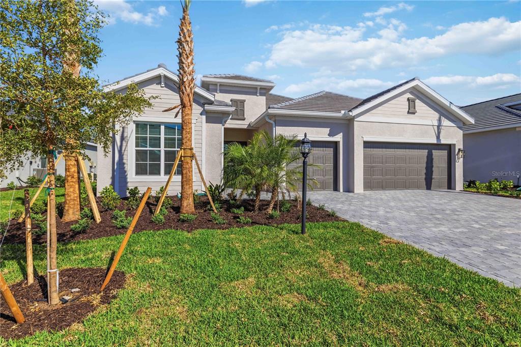 A single-story house with a gray exterior, a paved driveway, and a three-car garage — 5420 LIGHTNING WHELK LANE, BRADENTON, FL