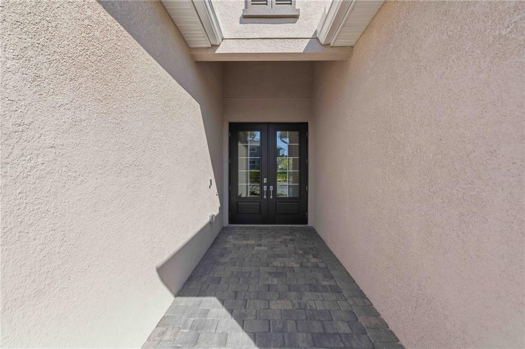 A covered entryway features a paver floor leading to a set of dark double doors — 5420 LIGHTNING WHELK LANE, BRADENTON, FL