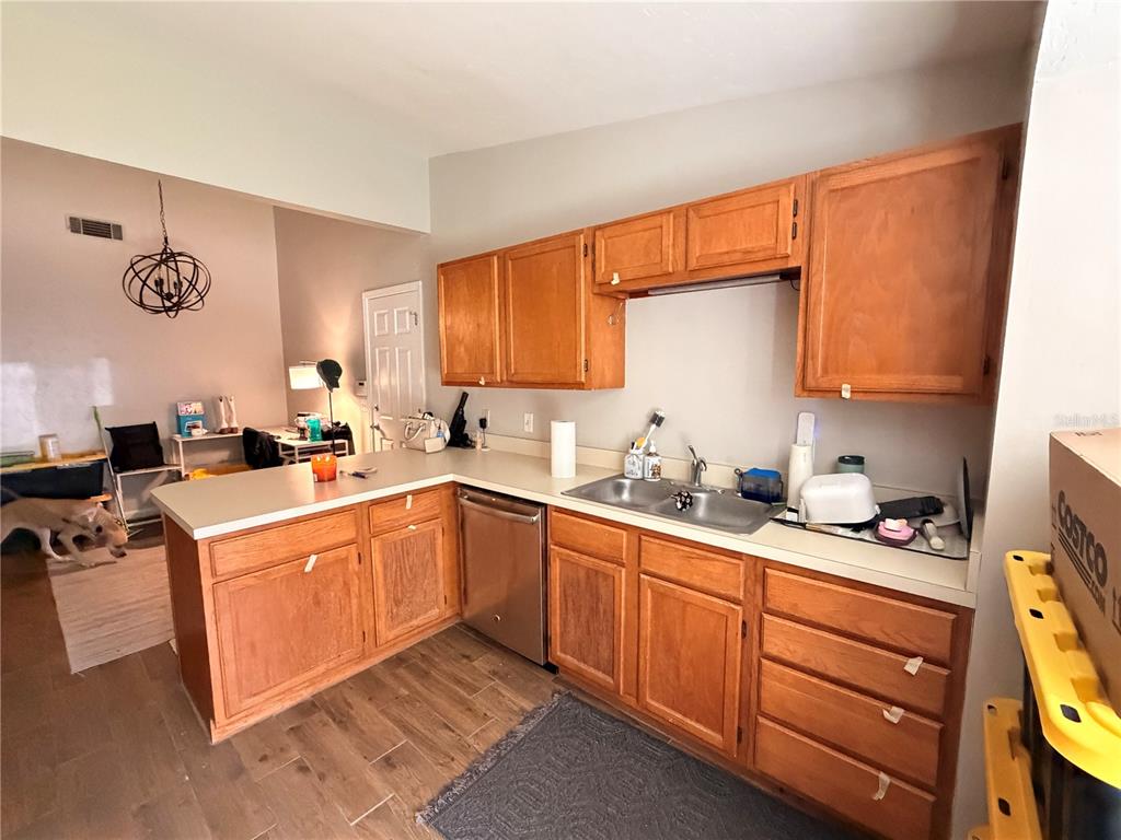A kitchen features wood cabinets, light countertops, a white refrigerator, and a breakfast nook area — 439 NW 50TH BOULEVARD, GAINESVILLE, FL