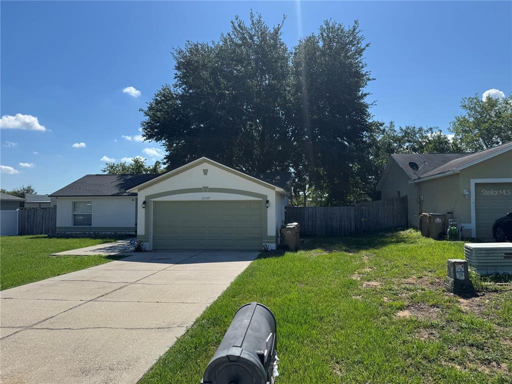 A single-story house with a light-colored exterior, a two-car garage, and a concrete driveway — 12249 WOODGLEN CIRCLE, CLERMONT, FL