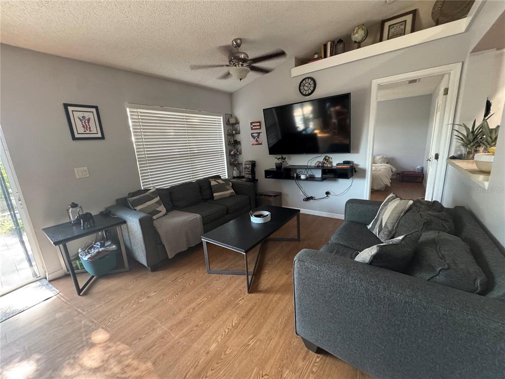 A living room features two dark gray sofas, a coffee table, and a wall-mounted television — 12249 WOODGLEN CIRCLE, CLERMONT, FL