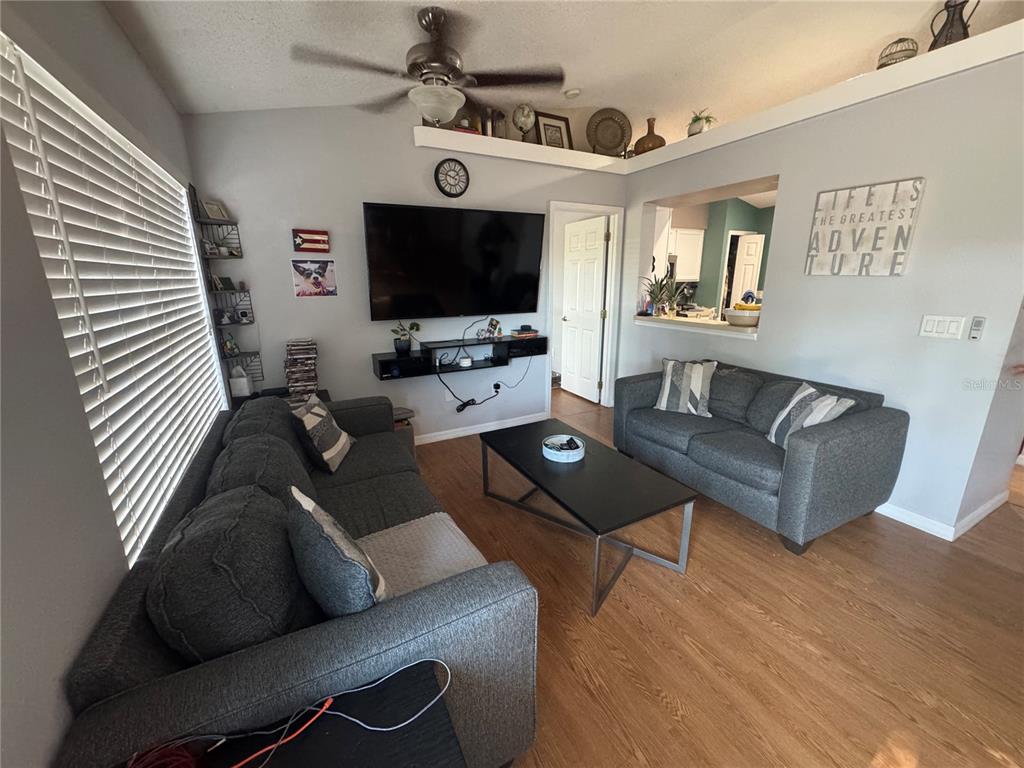 A living room features two gray sofas, a black coffee table, and a wall-mounted television — 12249 WOODGLEN CIRCLE, CLERMONT, FL
