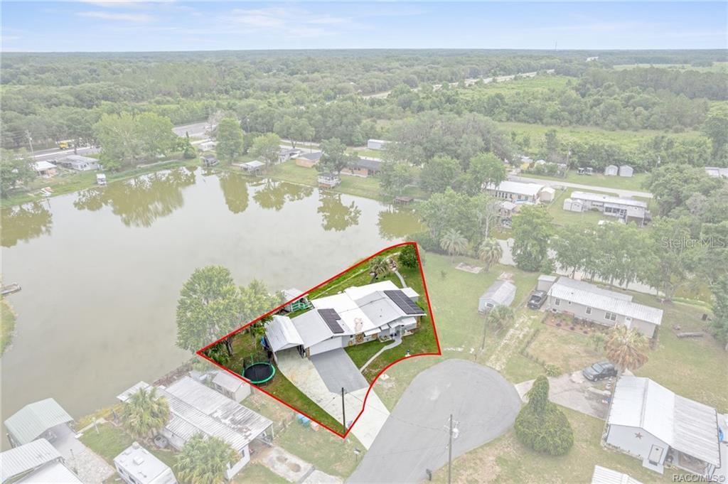 An aerial view shows a house with a red property boundary line beside a lake — 10115 E PERCH COURT, INVERNESS, FL