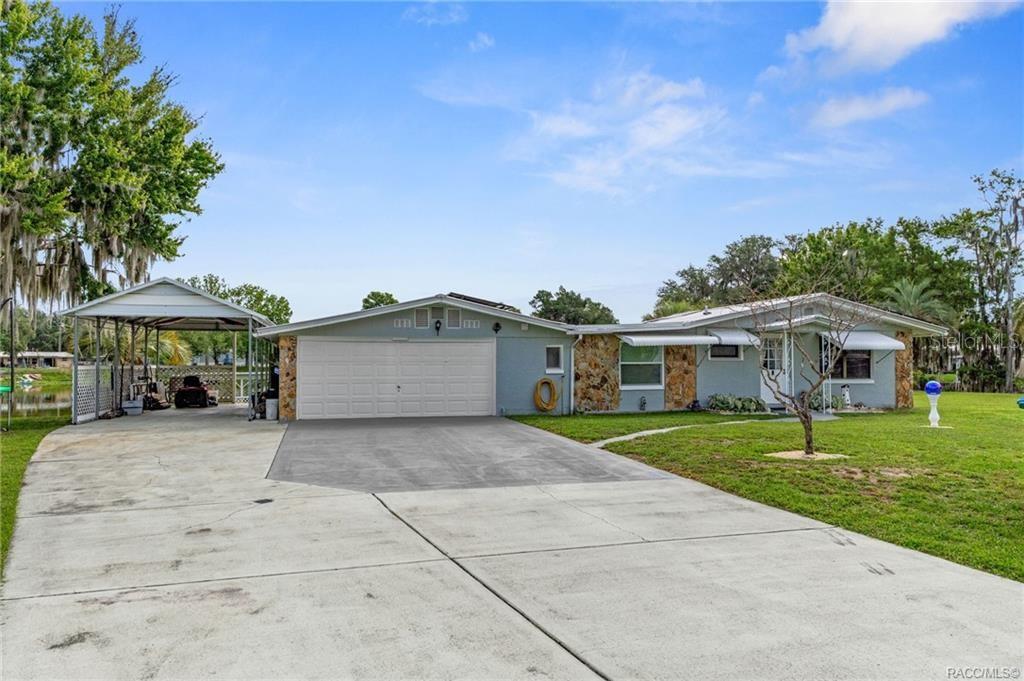 A single-story house with a two-car garage, attached carport, and stone accents on the exterior — 10115 E PERCH COURT, INVERNESS, FL