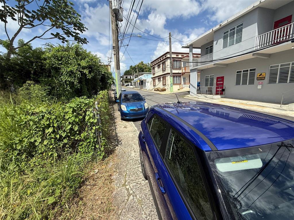 A street view shows two blue cars parked on a sidewalk next to a building — HOSTOS CABRERA ST., SAN SEBASTIAN, PR