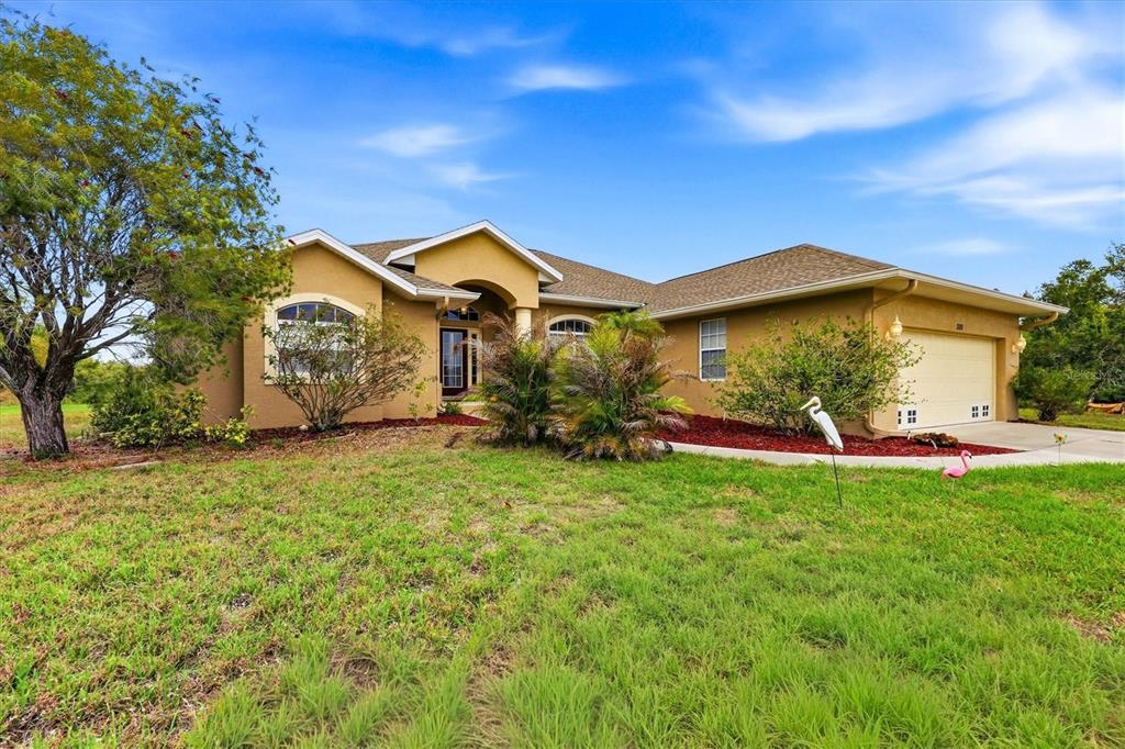 A single-story tan stucco house with a two-car garage and a large front lawn — 300 BAYTREE DRIVE, ROTONDA WEST, FL