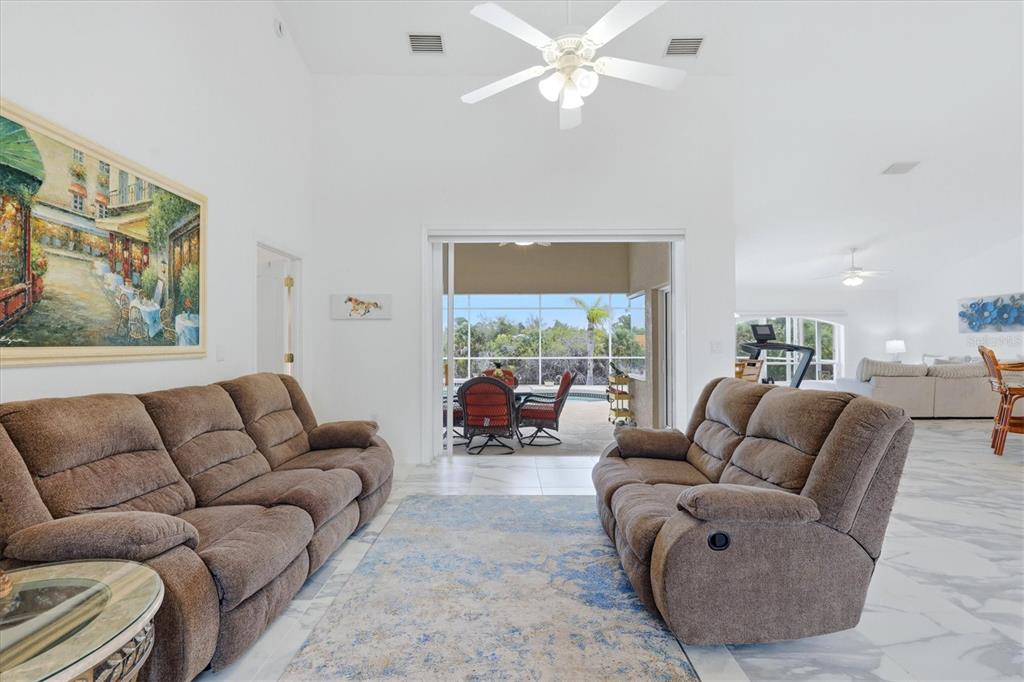 A living room with brown reclining sofas, a blue rug, and a view of a pool — 300 BAYTREE DRIVE, ROTONDA WEST, FL