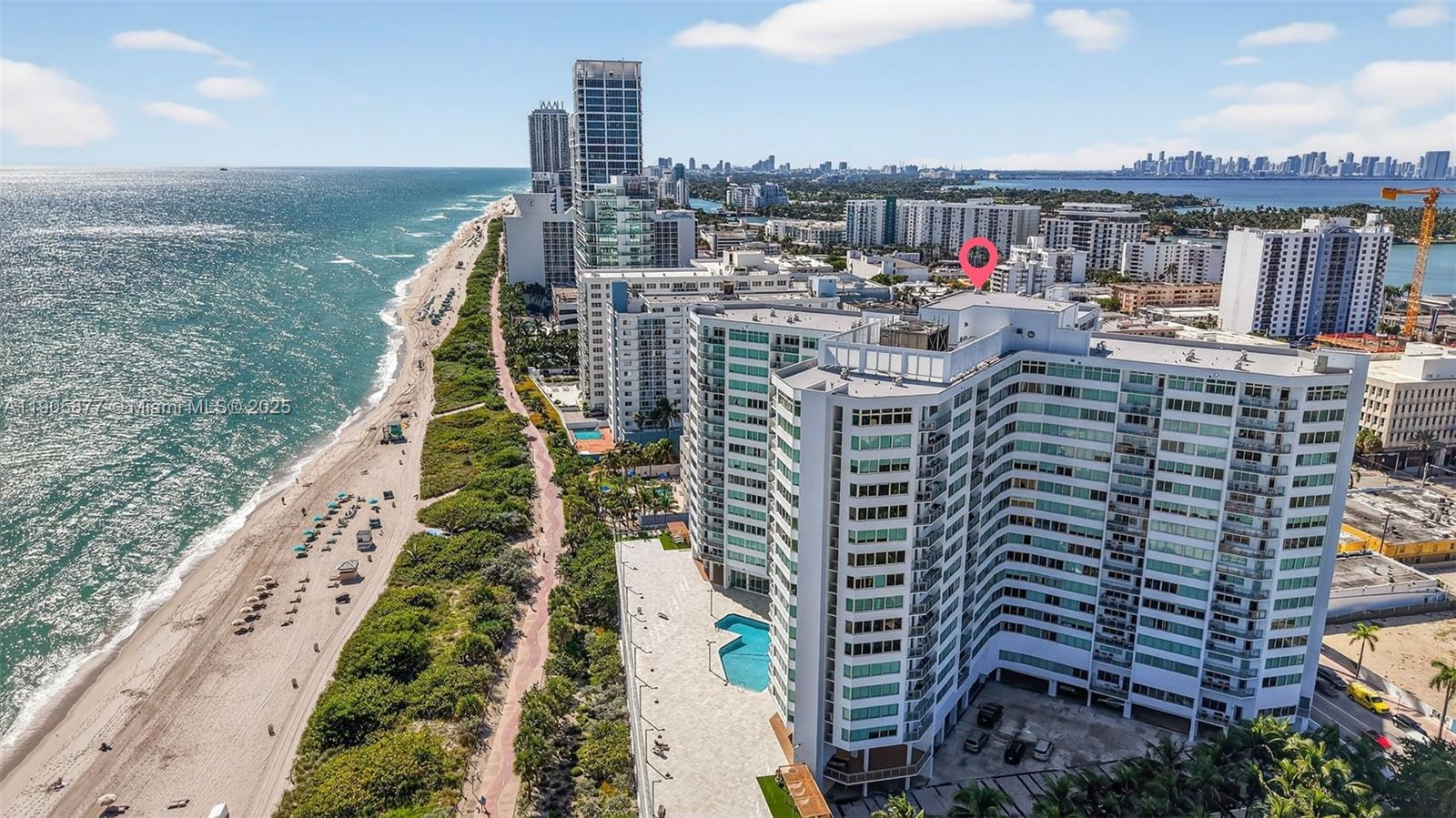 An aerial view shows a high-rise apartment building situated along a sandy beach — 7135 Collins Ave # 705, Miami Beach FL 33141, MIAMI BEACH, FL