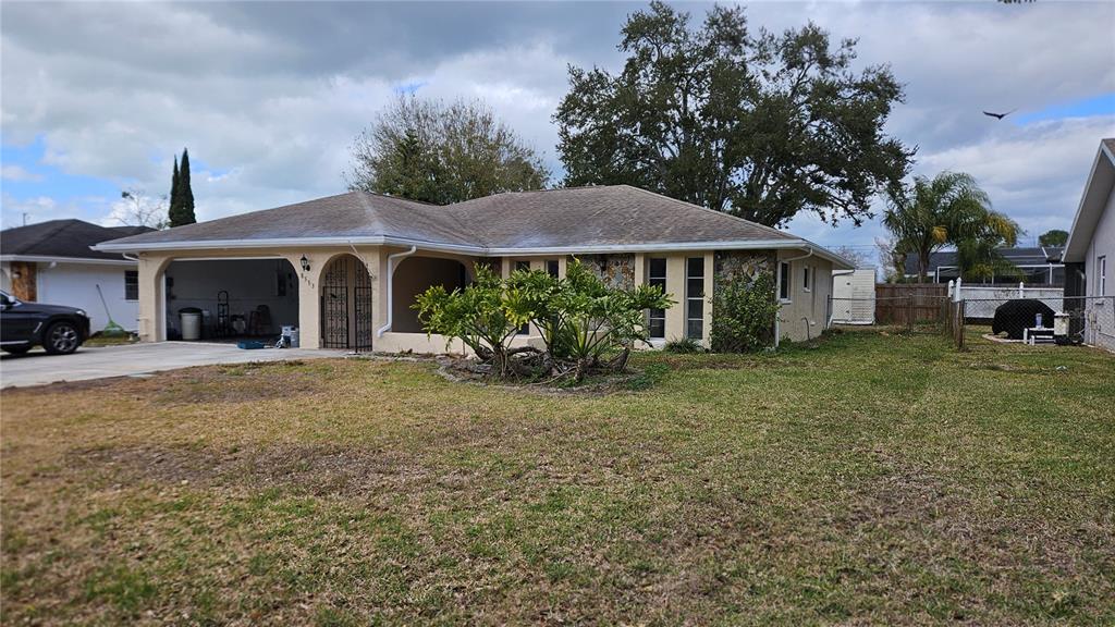 A single-story house with a carport, stone accents, and a large front yard — 8533 VIVA VIA DRIVE, HUDSON, FL